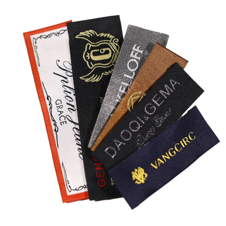 Assorted woven clothing labels with multicolored brand lettering and logos, arranged in a fan shape on a white background